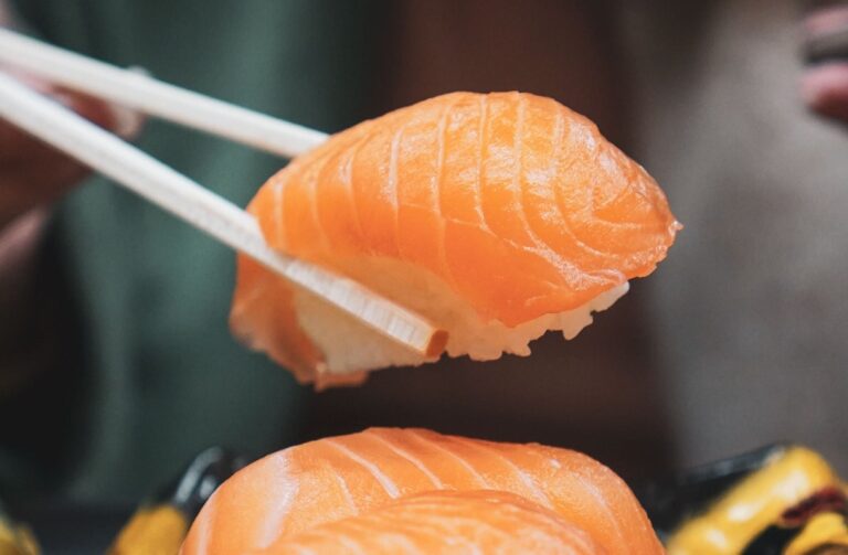 Is Sushi Japanese or Chinese? It’s Not What You Think salmon sushi held between choptsicks
