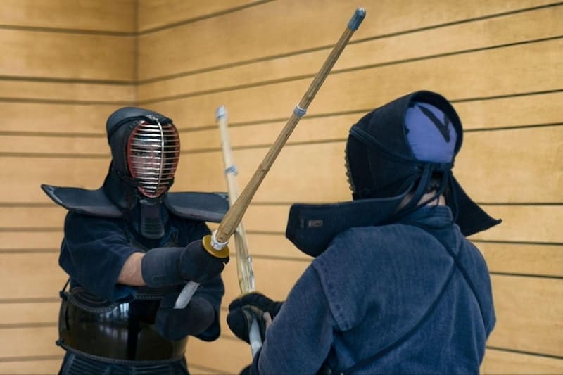 two kendo practitioners fighting in a gymnasium