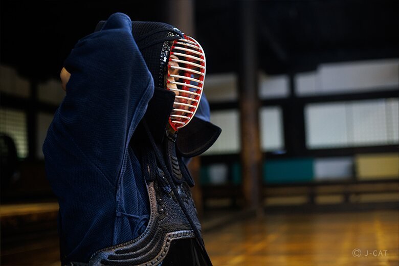 A kendo practitioner wearing protective armor and face mask in a dojo