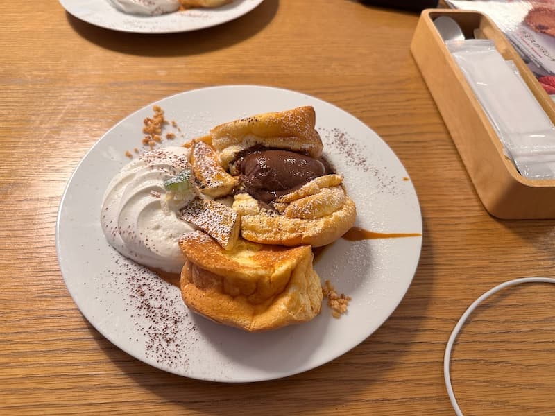 A plate of pancakes served with whipped cream and chocolate topping at Oiso Connect cafe in Oiso.