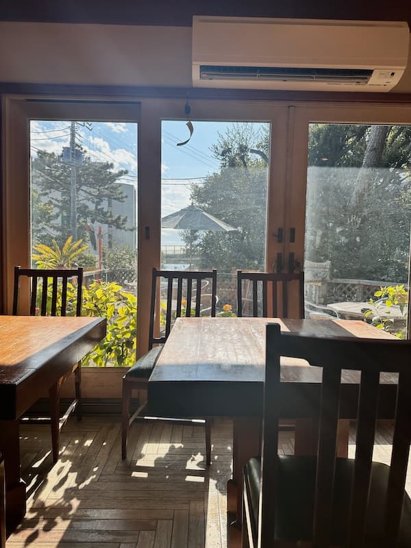 Interior of Hayashitei restaurant in Oiso, showing wooden tables and chairs with a view of the outdoor garden.