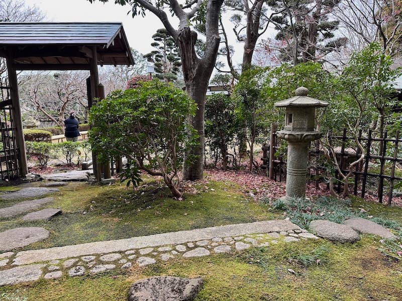 Garden with stone pathways, trees, and a traditional stone lantern at the tea house in Oiso Joyama Park.