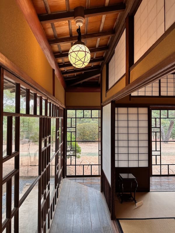 Hallway inside a traditional house at the Meiji Memorial Oiso Garden, featuring wooden floors and shoji screens.