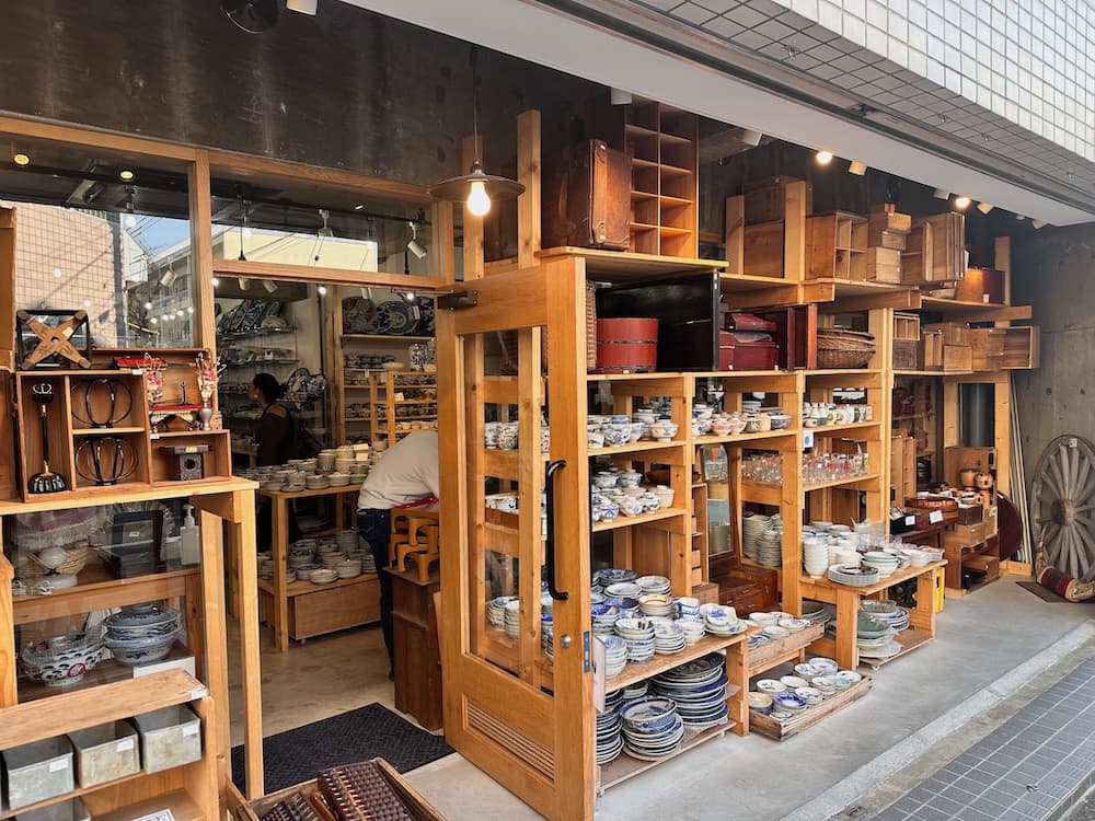 Exterior of a traditional ceramics shop in Kichijoji, with shelves of bowls, plates, and wooden boxes displayed outside and inside the store.