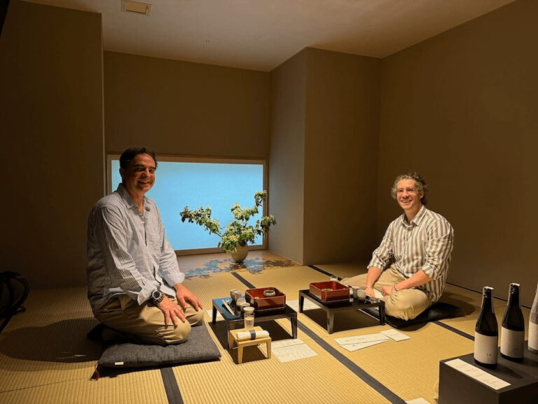 Two guests seated on tatami mats inside the private tasting room at Hasegawa Eiga, with sake and food in front of them.