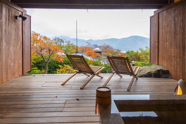 Open-air ryokan bath terrace at Hakone Gora Hanaougi with two wooden lounge chairs and mountain views