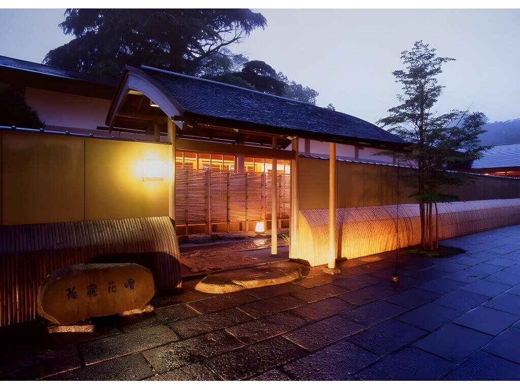 Entrance to Gora Kadan in Hakone at dusk with warm lights and wet stone paving