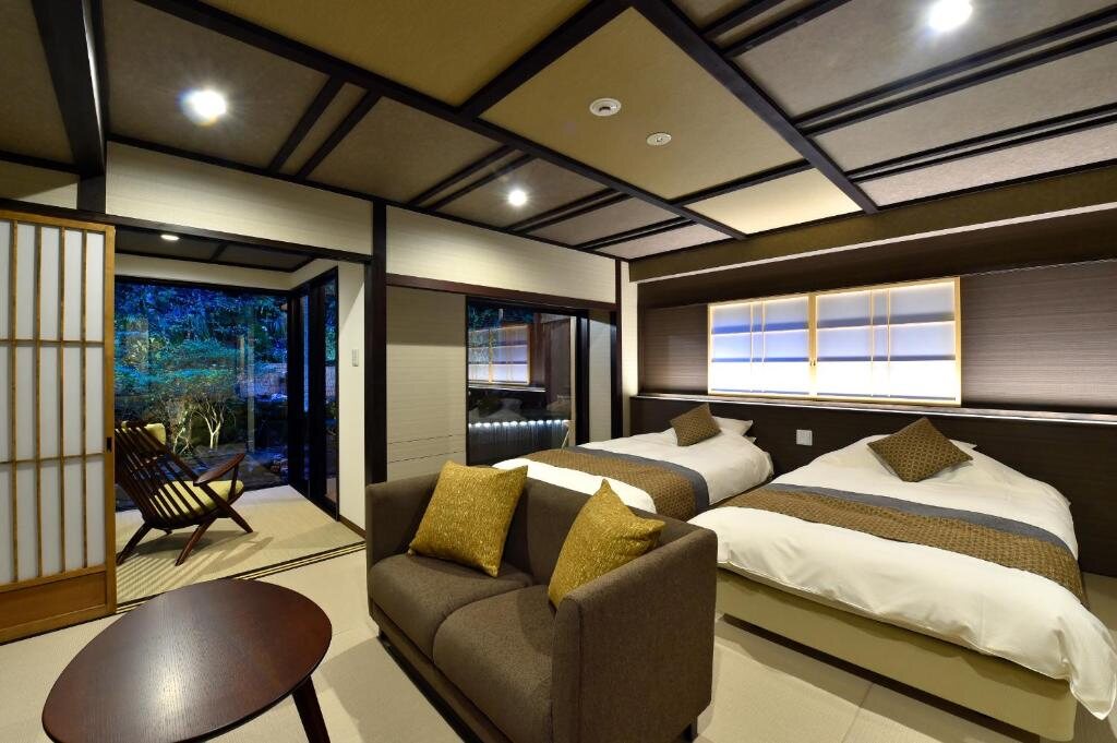 Japanese-style bedroom at Sumiya Kihoan in Kameoka with twin beds, sofa, and garden view
