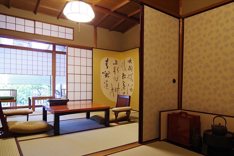 Traditional Japanese tatami room at Hiiragiya ryokan in Kyoto with low table, floor cushions, shoji screens, and calligraphy wall art