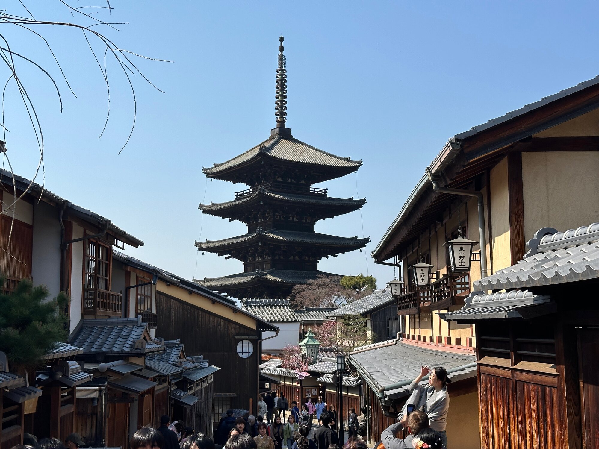 A five-story pagoda rising above a street lined with traditional buildings in Kyoto’s Yasaka area, with people gathered below.