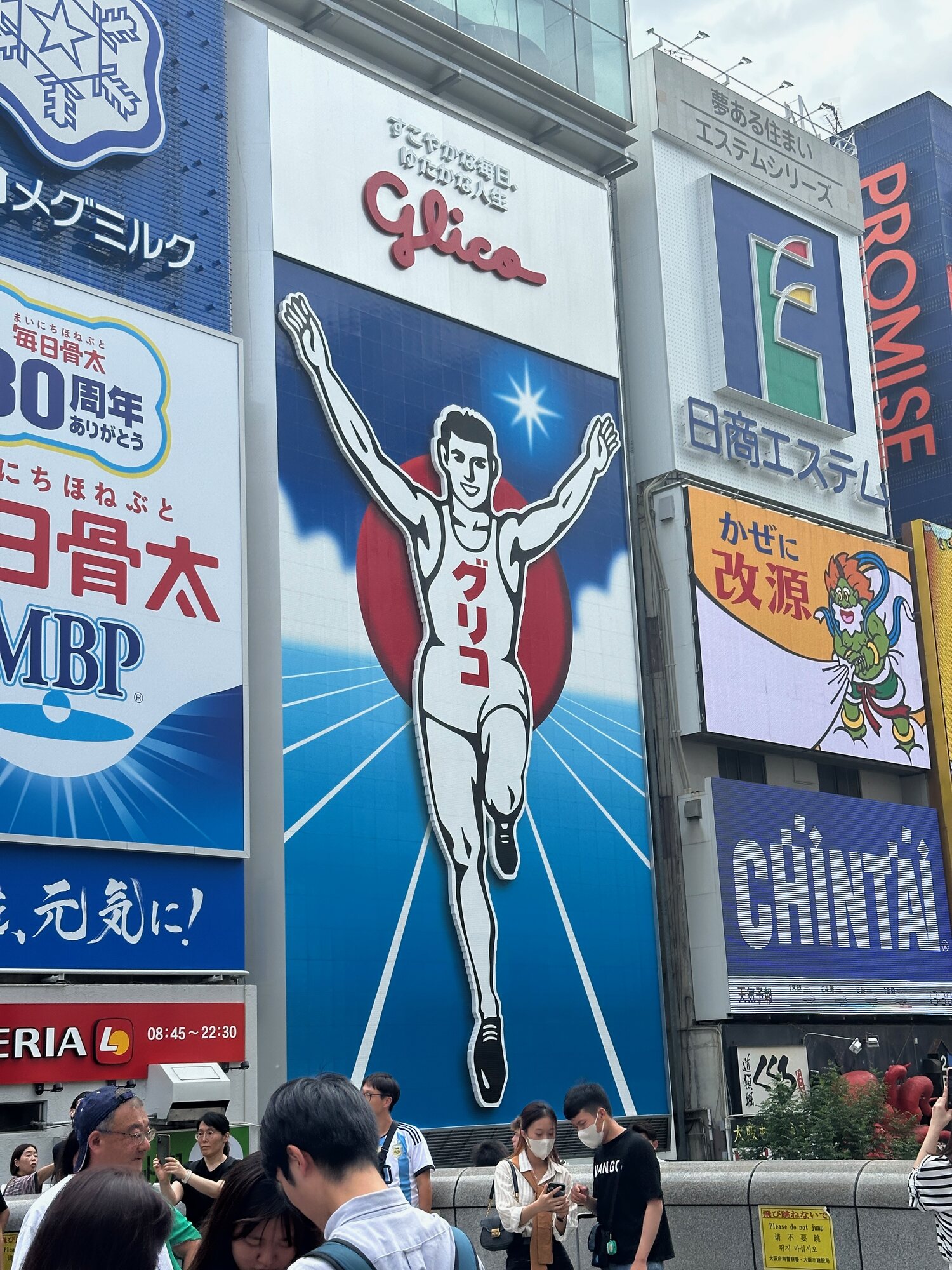 Dotonbori Glico sign in Osaka with a large running man billboard and surrounding storefront ads