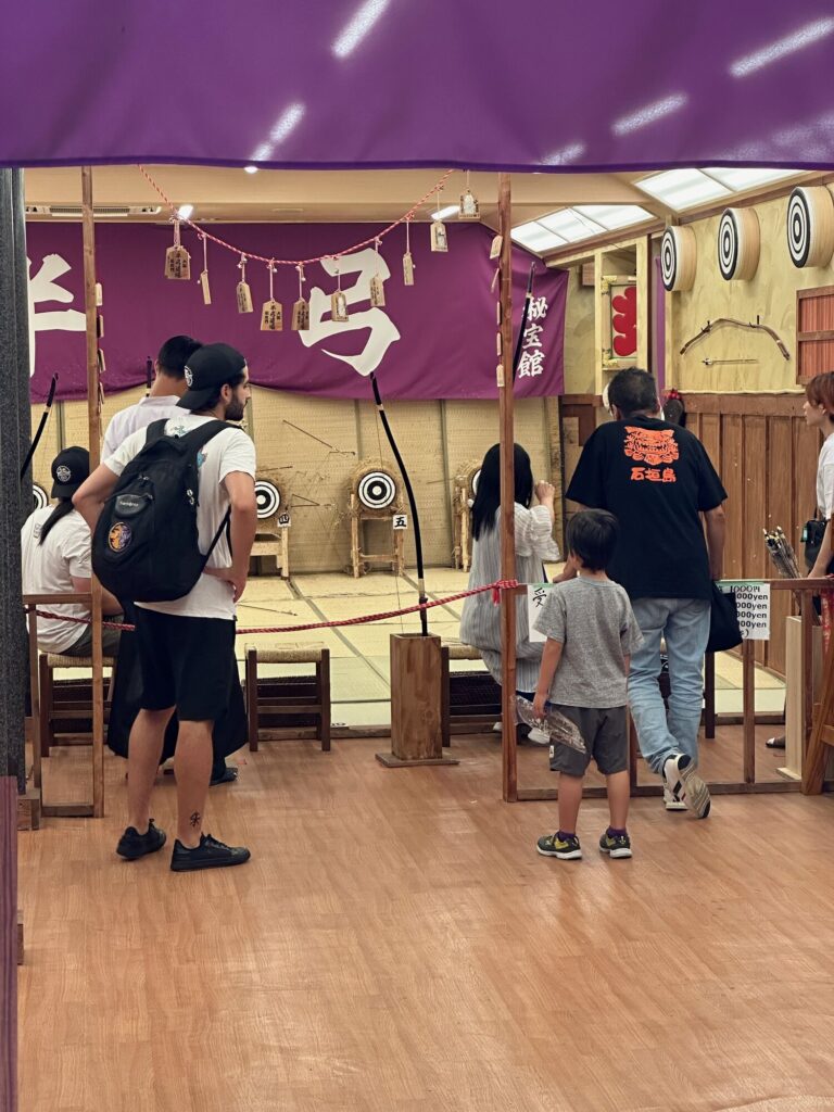 People watching an archery demonstration at a traditional Japanese kyudo range.