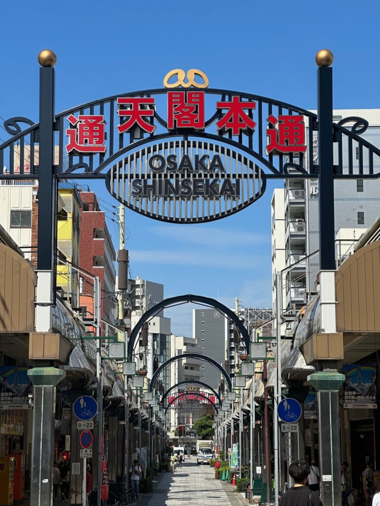 Osaka Tsutenkaku Jan Jan Yokocho shopping arcade entrance with large “OSAKA SHINSEKAI” arch signs overhead