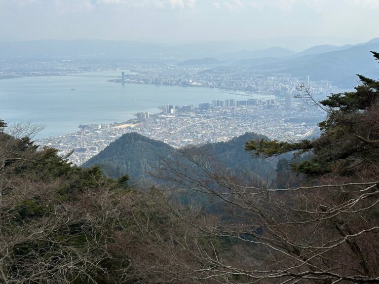 10-Day Japan Itinerary for First-Time Visitors: What to See and What to Cut View over Lake Biwa and Otsu city from a mountainside lookout, with pine trees in the foreground and a bridge crossing the lake