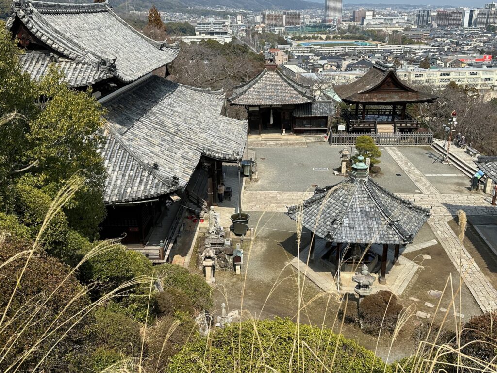 View from above of Otsu Onjoji Temple grounds with traditional tiled-roof buildings and a courtyard, looking toward the city in the background