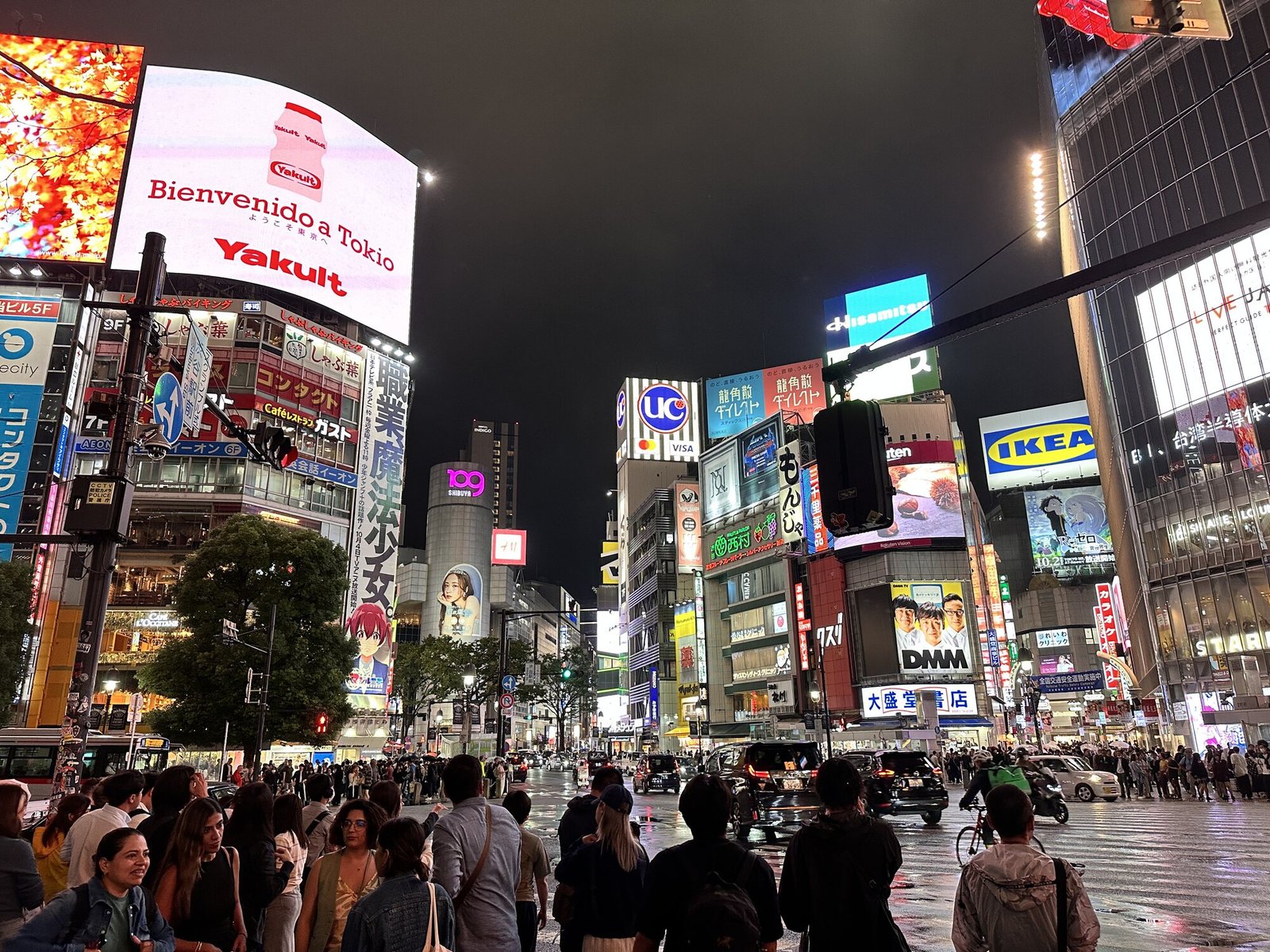 Shibuya Scramble Crossing in Tokyo at night with crowds, street traffic, and large illuminated billboards including an IKEA sign