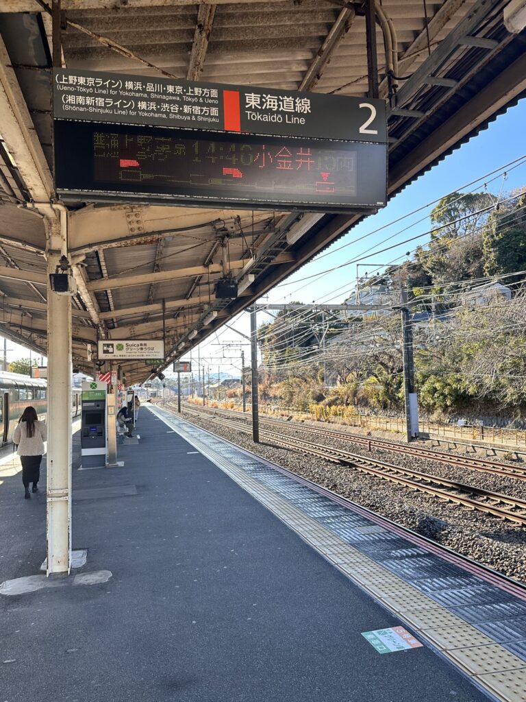 Tokyo train station platform sign for the Tokaido Line with a digital departure board and tracks