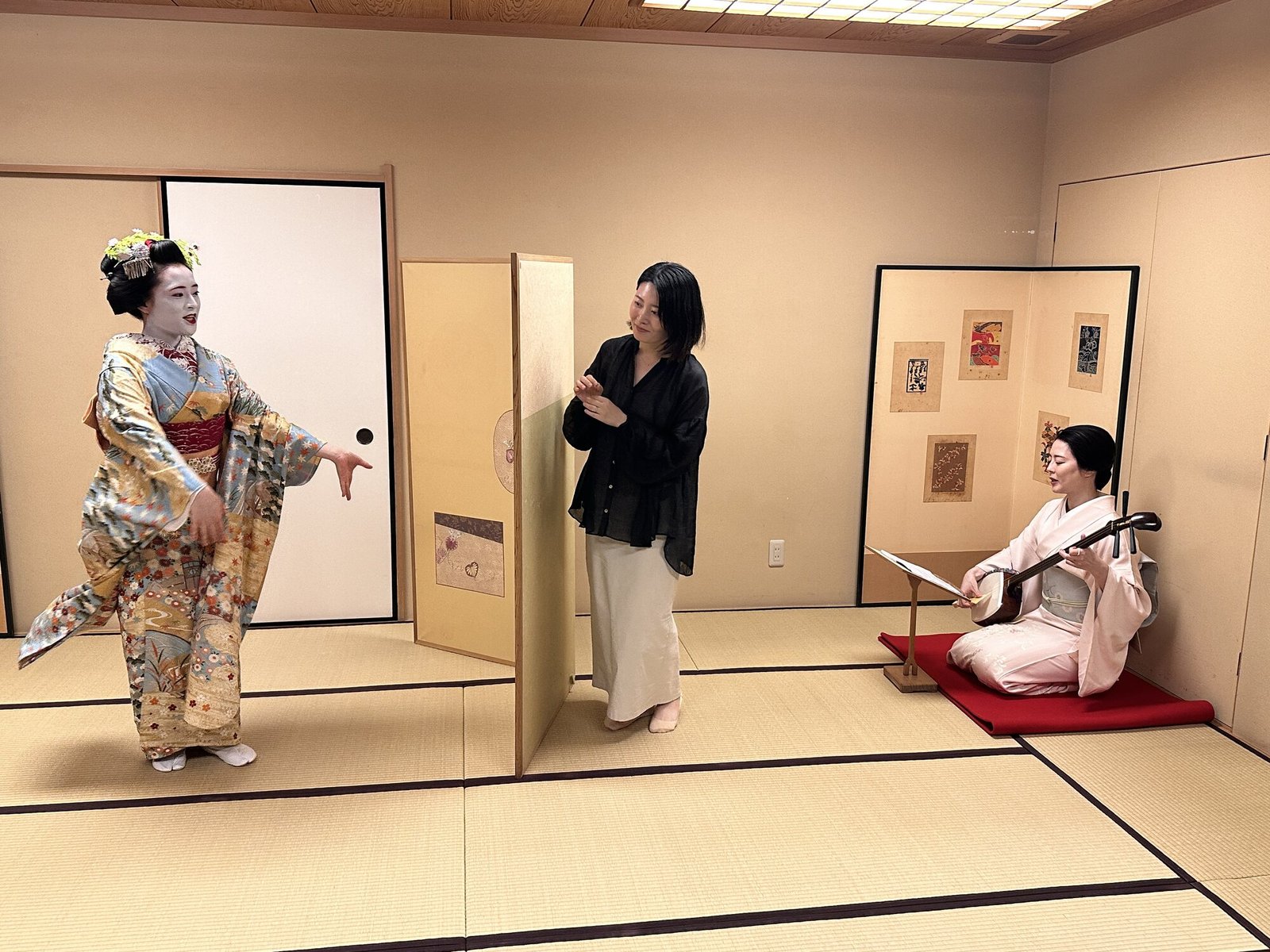 Geisha performance in a tatami room at a Tokyo ryotei, with one performer dancing and another playing shamisen while a guest watches