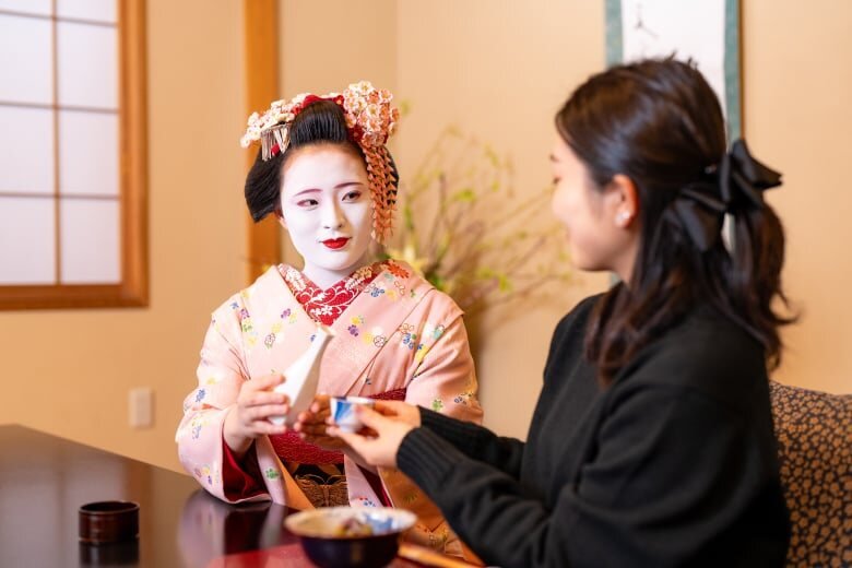 Geisha serving sake to a woman at a ryotei in Tokyo