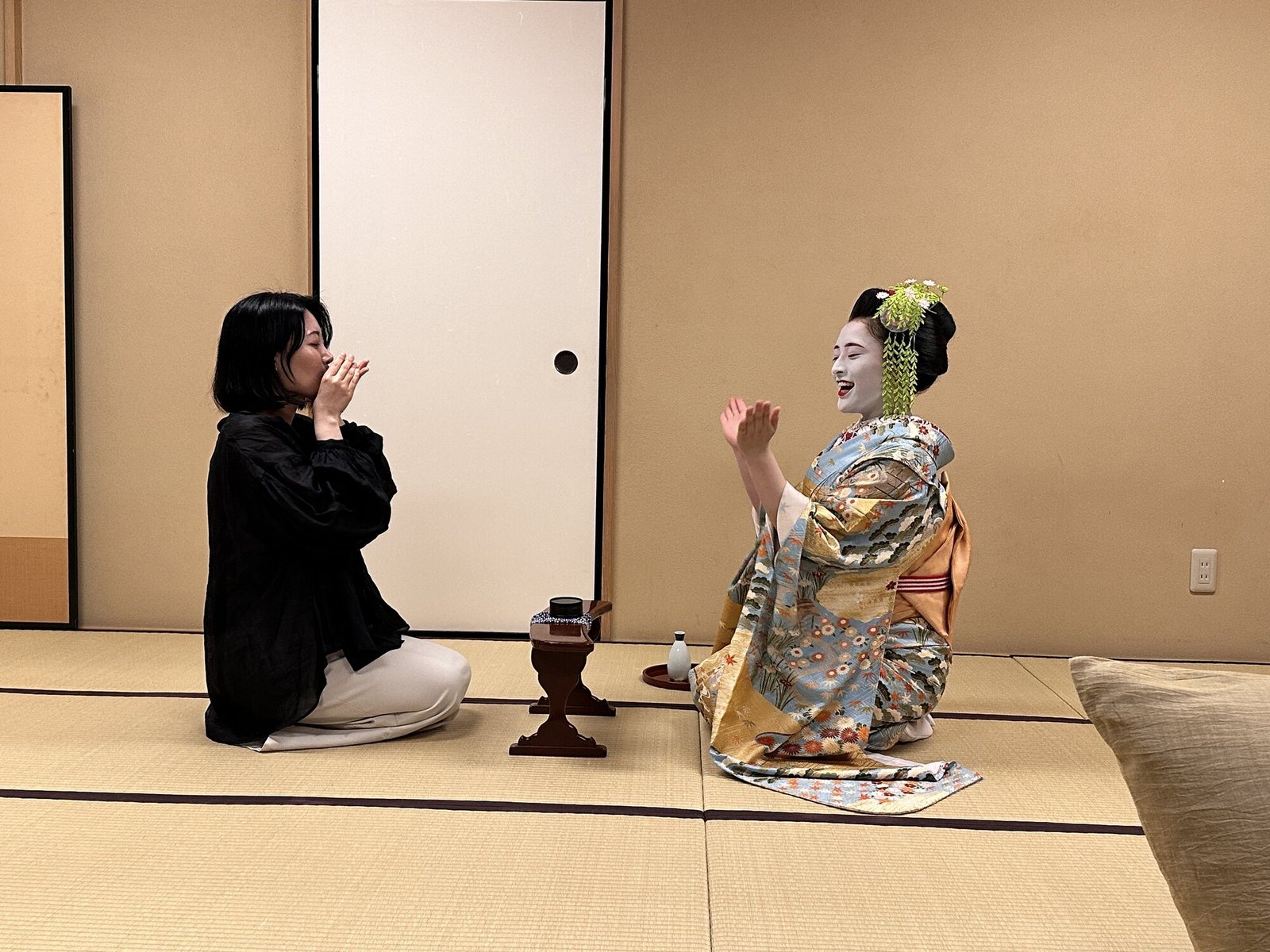 Woman in a kimono performing a geisha-style game in a tatami room in Tokyo