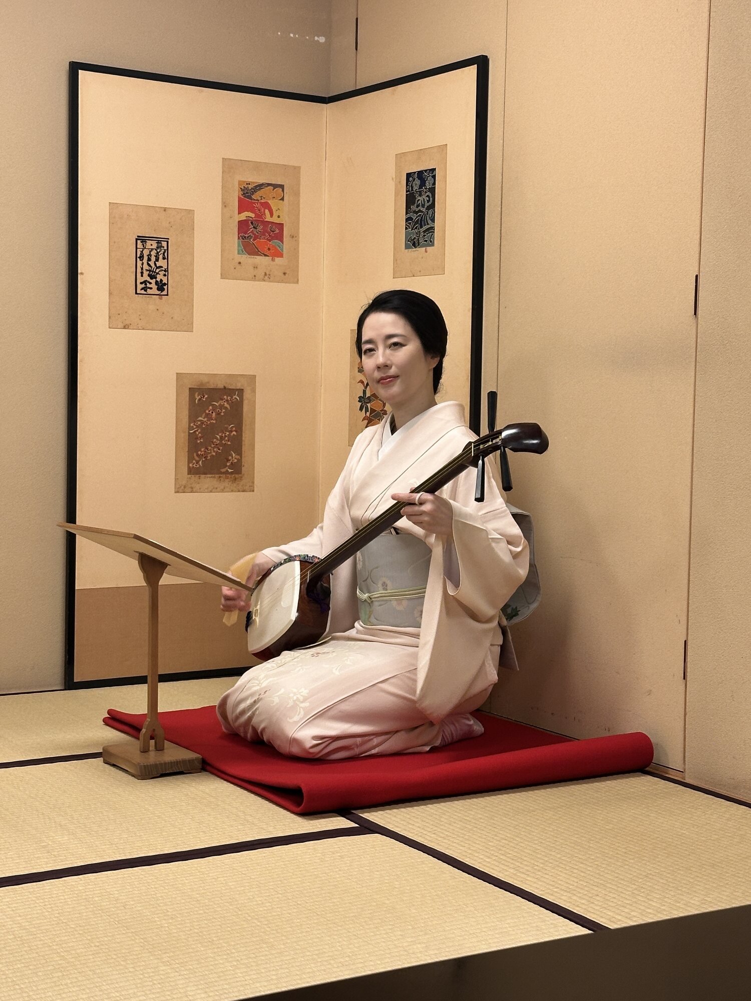 Kimono-clad shamisen performer seated on a tatami mat in a traditional Tokyo ryotei room