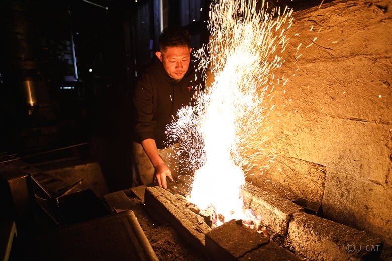 Swordsmith working beside the furnace at Asano Kajiya in Gifu