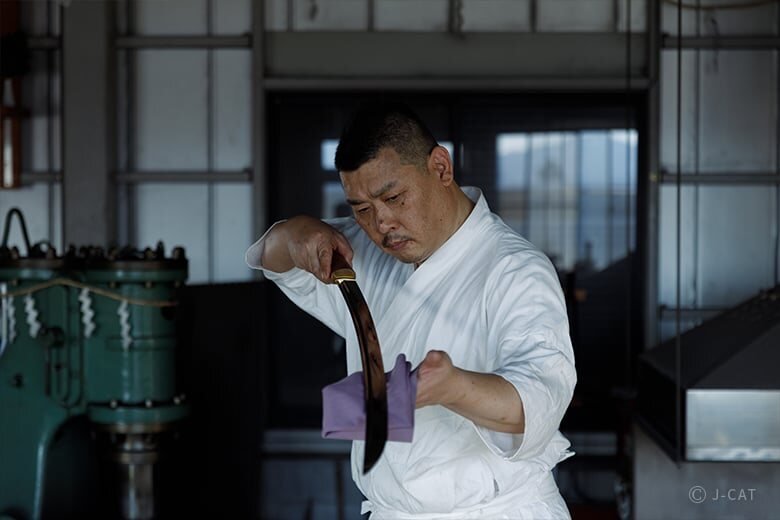 Fusahiro Shimojima examining a katana at his swordsmith workshop in Saitama
